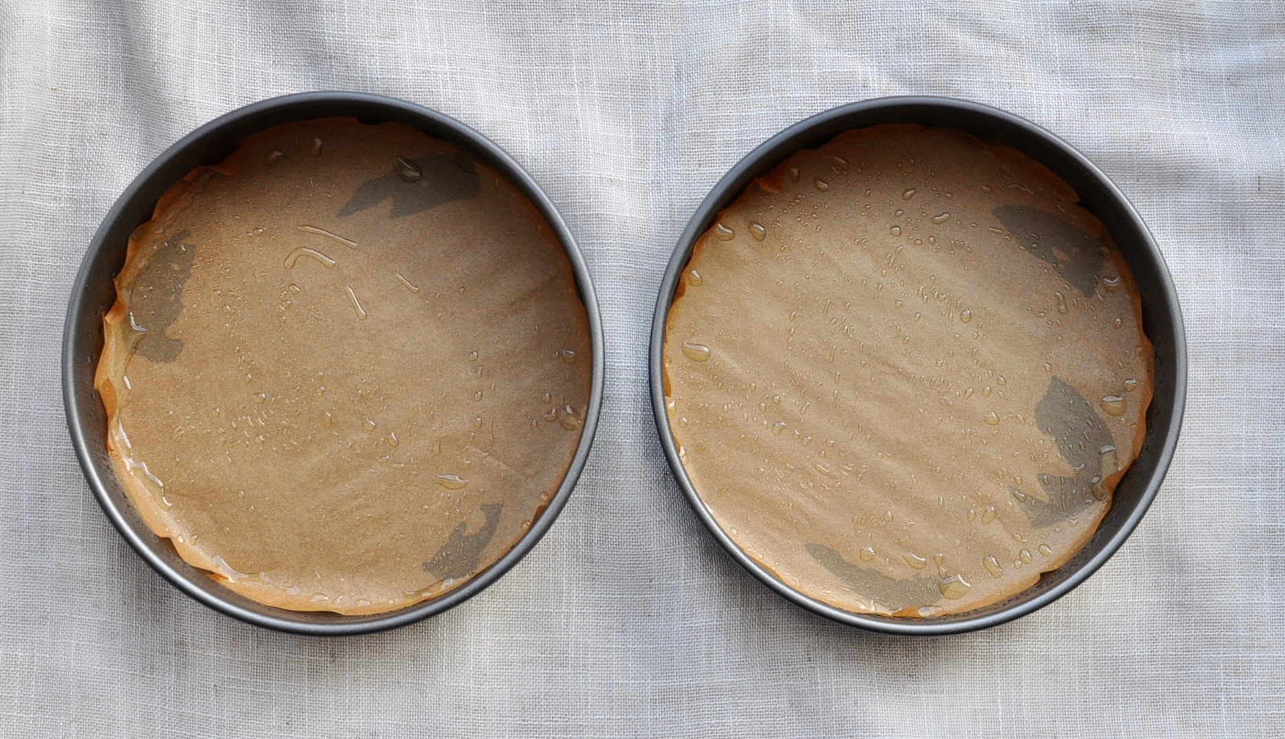 Two cake pans lined with parchment paper and greased